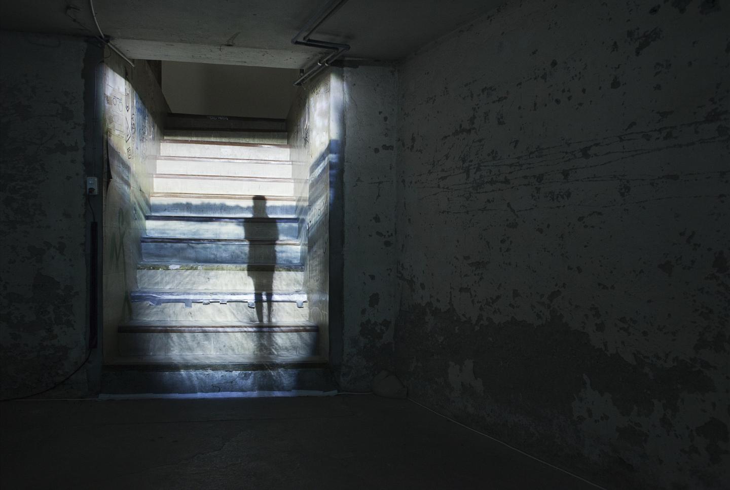 projection of figure (artist) standing in front of ocean, projected on staircase