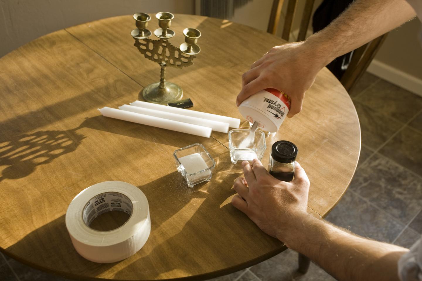 artist pouring salt into glass bowl on table