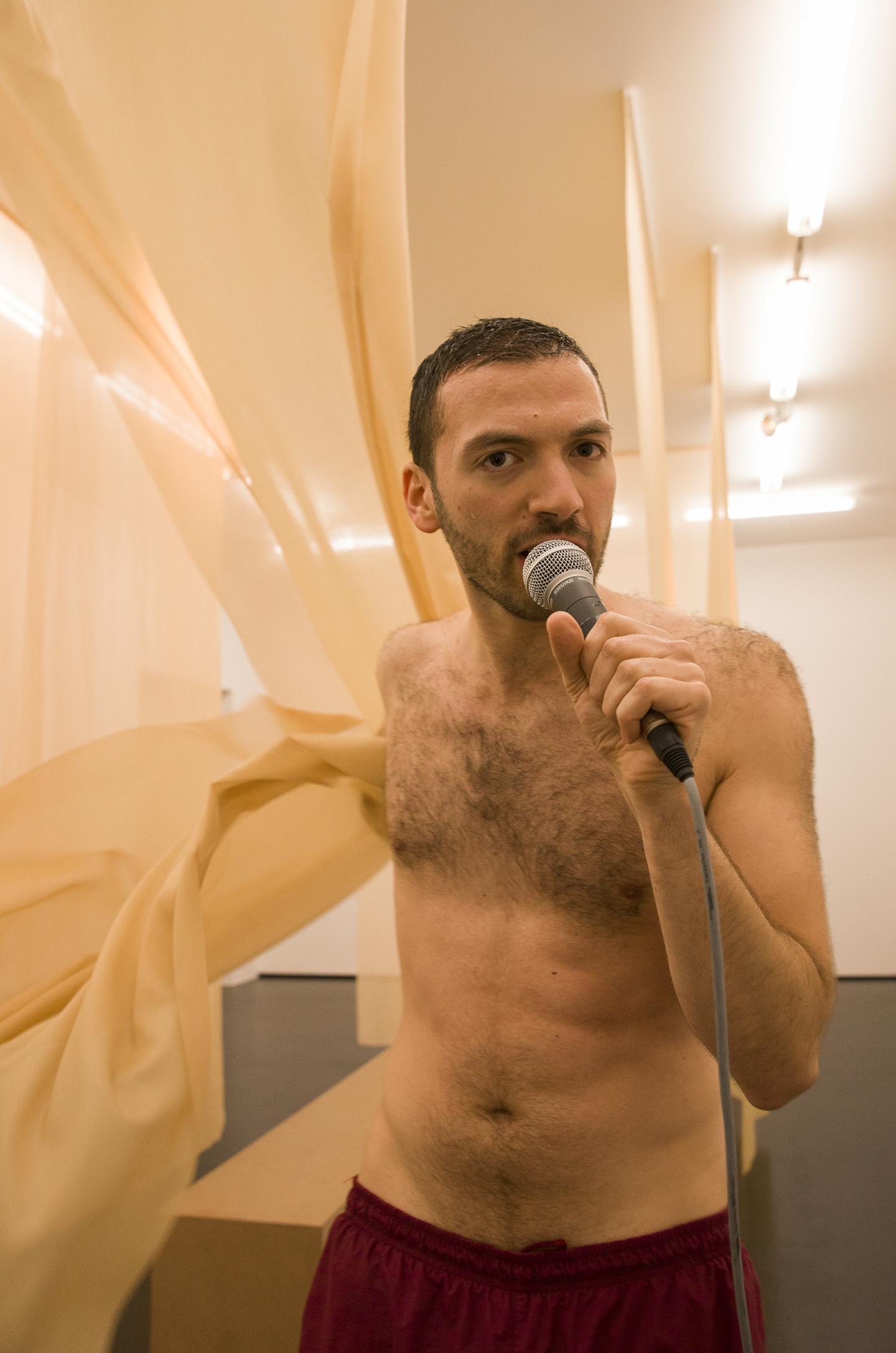 artist speaking into microphone and grabbing transparent curtain