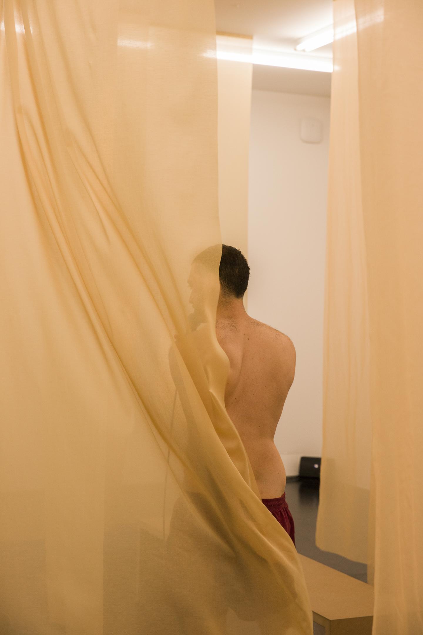 artist walking between transparent curtains