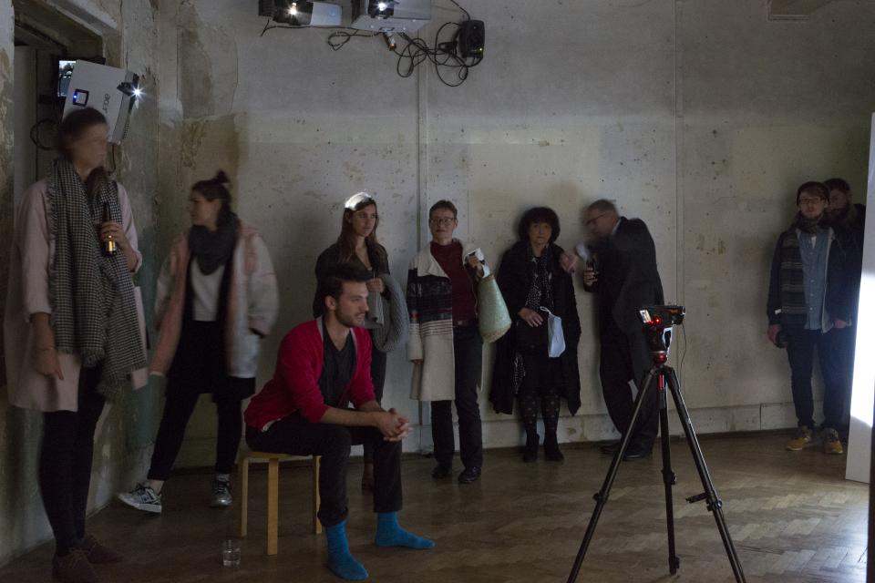 artist sitting in front of video camera, surrounded by audiene