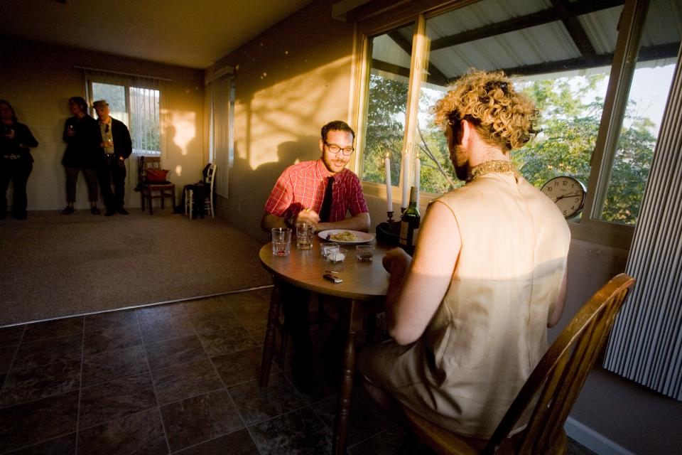 artist sitting with guest at dinner table in sunset light