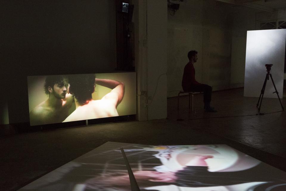 video projections on wall and floor, performer sitting in between