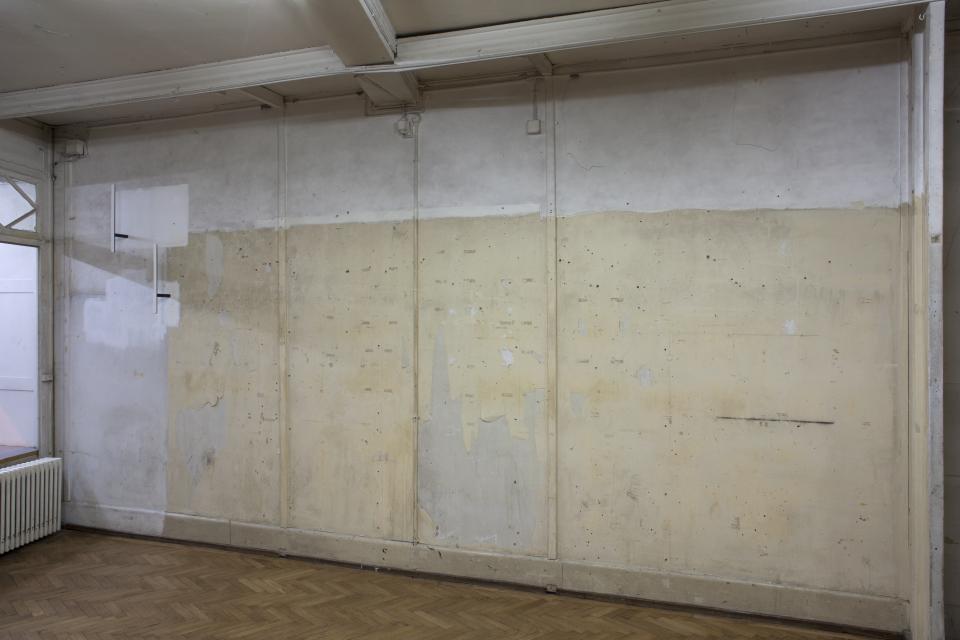 two batons painted white on surface stuck into wall, where it is painted white