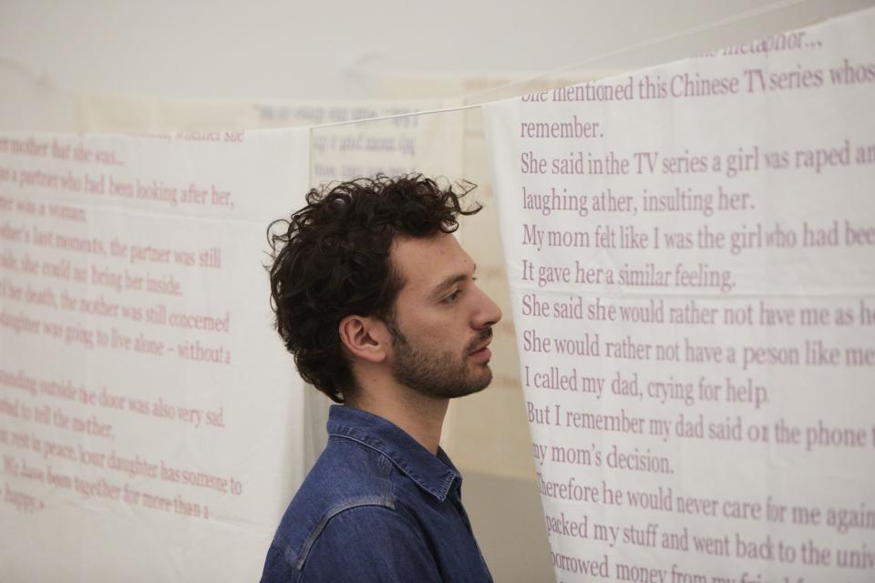 artist standing in front of white fabrics with colored text printed them
