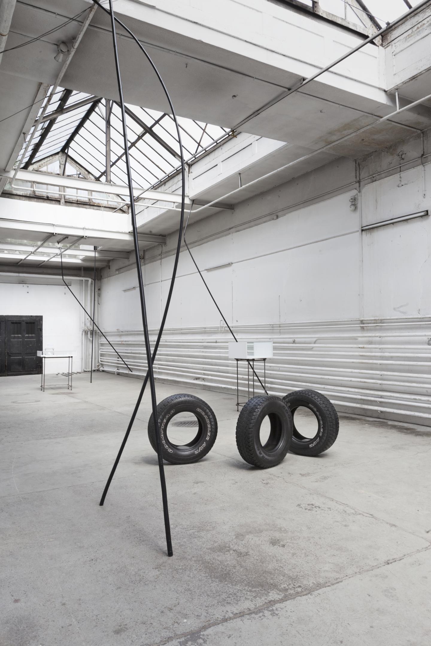 large black stick and tires installed in exhibition space